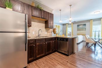 A modern kitchen with wooden cabinets and a stainless steel refrigerator.